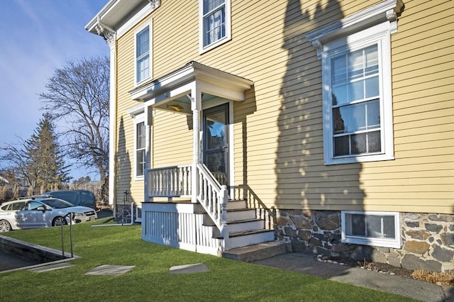 view of exterior entry featuring a lawn