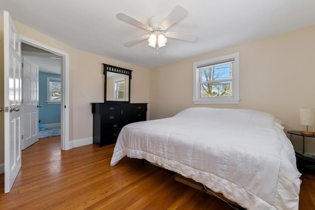 bedroom with hardwood / wood-style flooring, ceiling fan, and multiple windows