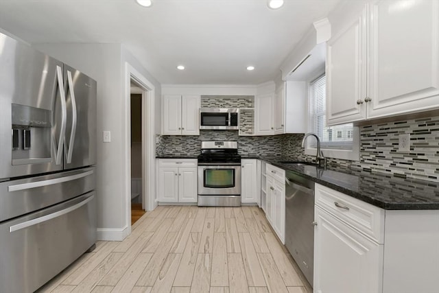 kitchen with stainless steel appliances, sink, dark stone countertops, and white cabinets