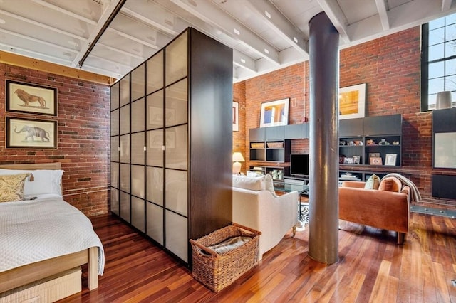 bedroom featuring brick wall, wood-type flooring, and beam ceiling