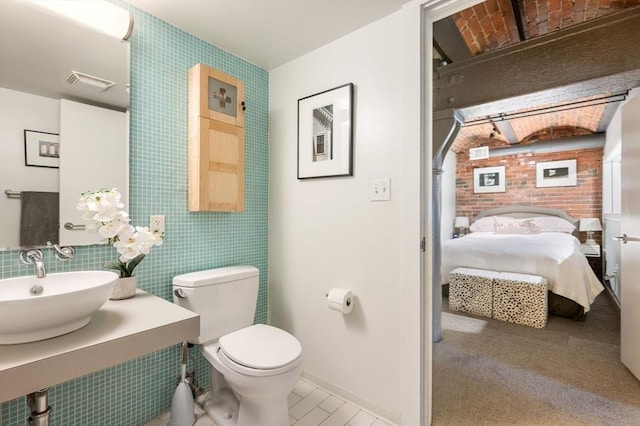 bathroom featuring a sink, ensuite bathroom, toilet, and baseboards