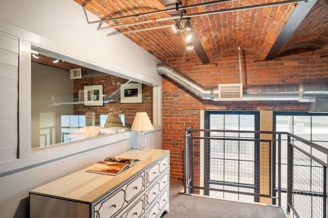 hallway featuring brick ceiling, brick wall, and carpet floors