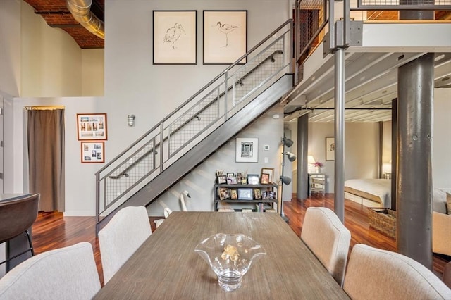 dining space with stairs, wood finished floors, a towering ceiling, and baseboards