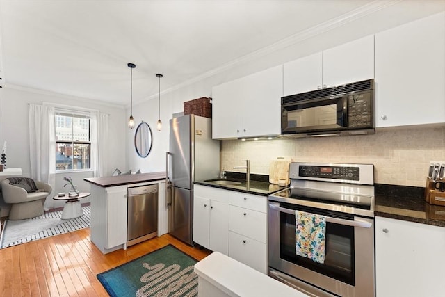 kitchen featuring dark countertops, appliances with stainless steel finishes, and ornamental molding