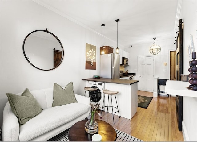 living area with crown molding and light wood-style floors