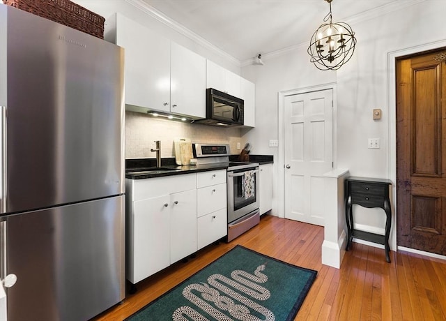 kitchen with hardwood / wood-style flooring, a sink, dark countertops, appliances with stainless steel finishes, and crown molding