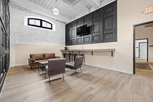 interior space with light wood finished floors, baseboards, and beam ceiling