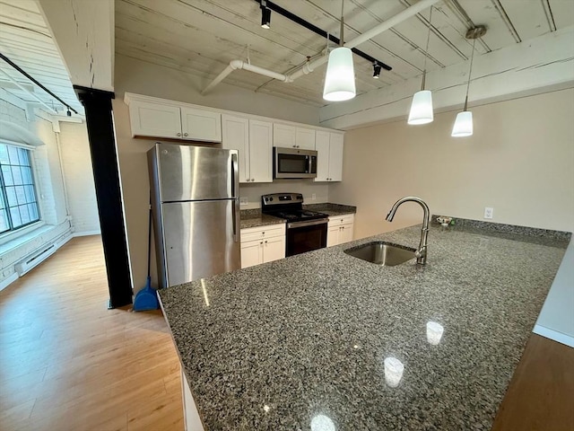 kitchen with white cabinets, light wood-style flooring, appliances with stainless steel finishes, decorative light fixtures, and a sink