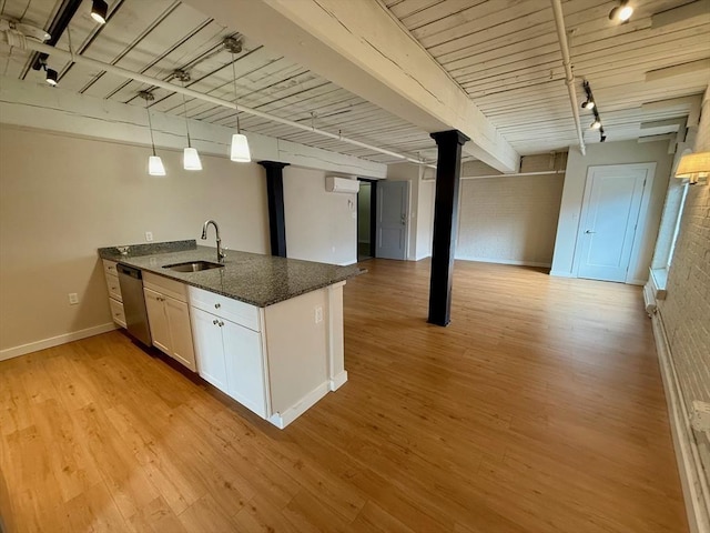 kitchen featuring dark stone counters, dishwasher, white cabinetry, pendant lighting, and a sink