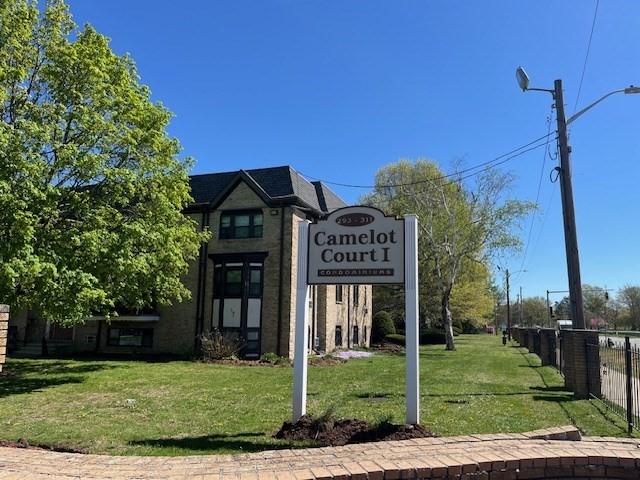 community / neighborhood sign with a lawn and fence