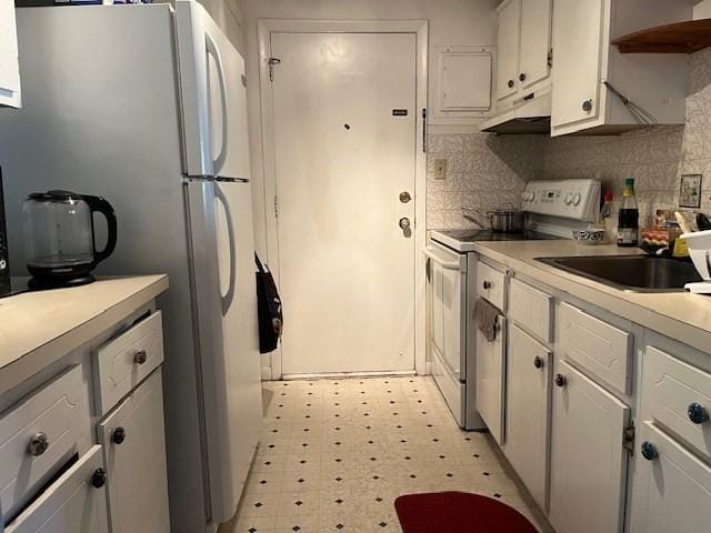 kitchen featuring white appliances, light countertops, light floors, backsplash, and under cabinet range hood