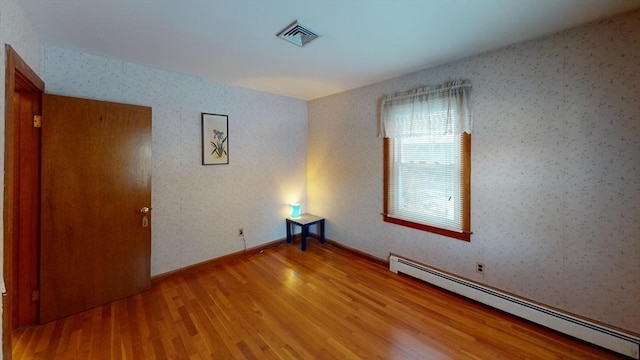 unfurnished room with light wood-type flooring and baseboard heating