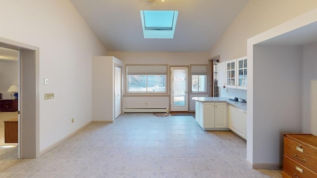 kitchen with white cabinetry, a baseboard heating unit, light tile patterned floors, and lofted ceiling with skylight