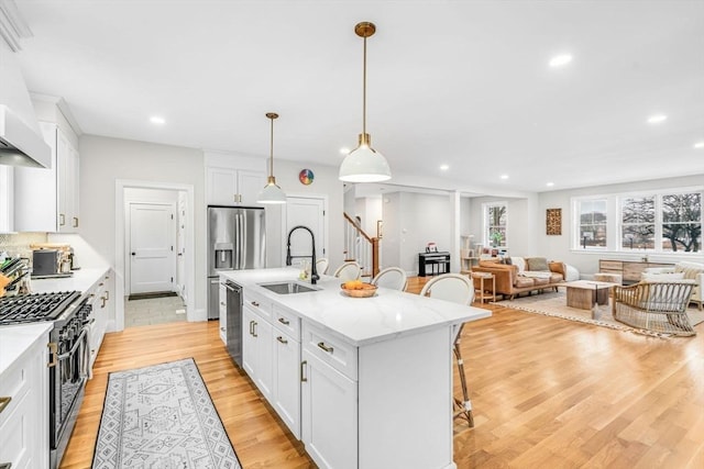 kitchen featuring a breakfast bar area, stainless steel appliances, a sink, white cabinetry, and light wood-type flooring