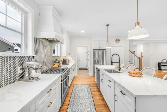 kitchen with a sink, white cabinetry, appliances with stainless steel finishes, light wood-type flooring, and custom exhaust hood