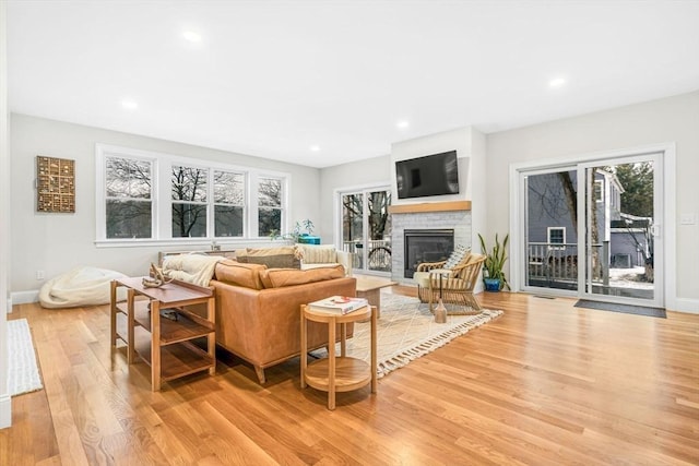 living area with light wood-type flooring, a fireplace, baseboards, and recessed lighting