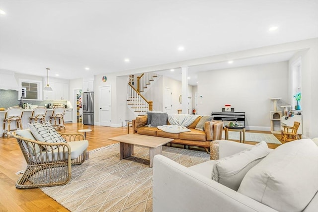 living area with baseboards, stairway, light wood-type flooring, and recessed lighting