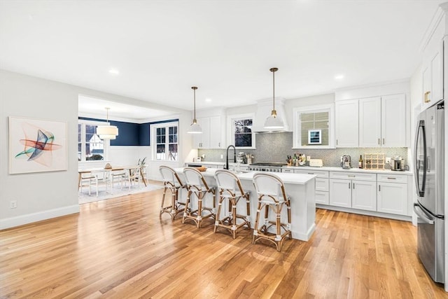 kitchen with tasteful backsplash, stainless steel appliances, light countertops, light wood-style floors, and white cabinetry