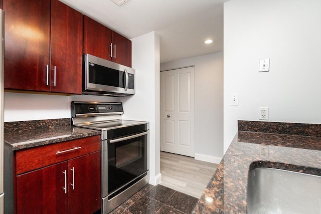 kitchen featuring sink, dark hardwood / wood-style flooring, stainless steel appliances, and dark stone counters