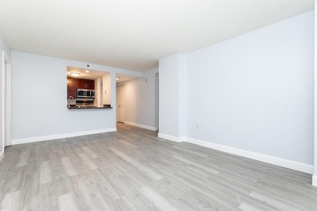 unfurnished living room with light hardwood / wood-style flooring and sink