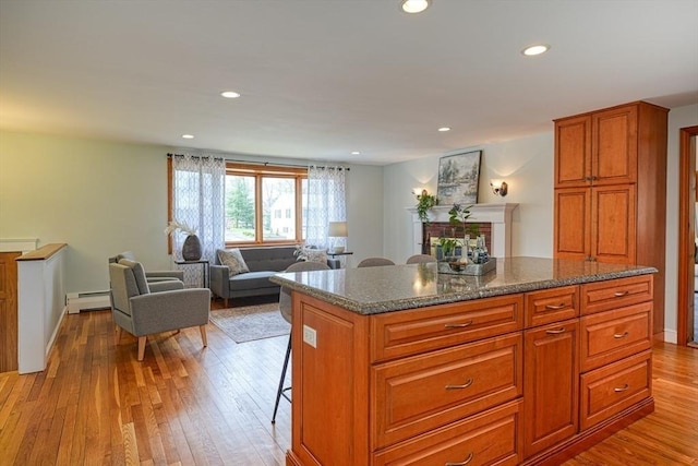 kitchen with a baseboard radiator, light wood-type flooring, a kitchen island, and recessed lighting