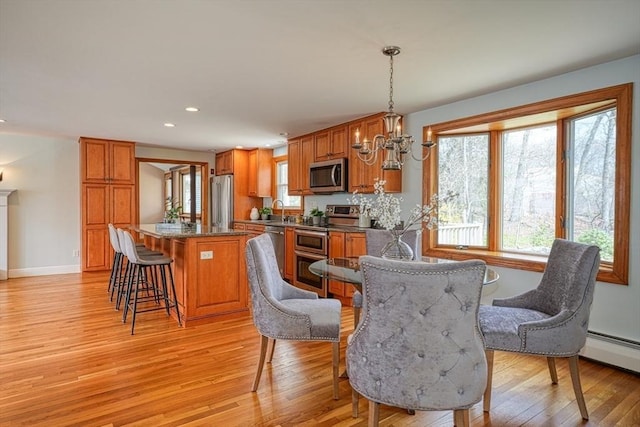 dining area with baseboard heating, a chandelier, light wood-type flooring, baseboards, and recessed lighting