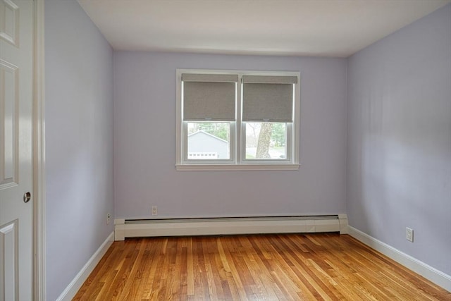 unfurnished room with a baseboard heating unit, baseboards, and light wood-type flooring