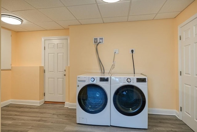 clothes washing area featuring wood finished floors, baseboards, and separate washer and dryer
