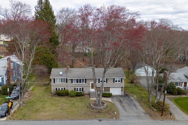 split foyer home featuring a front lawn, aphalt driveway, and a garage