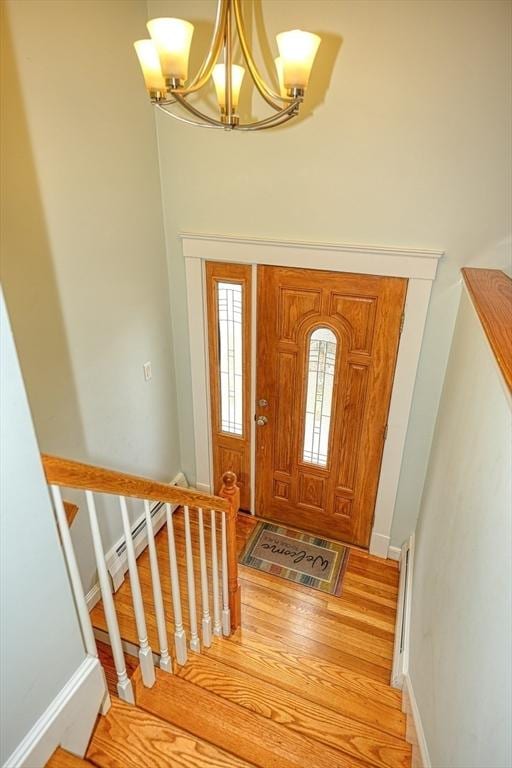 foyer featuring a chandelier, light wood-type flooring, baseboards, and stairs