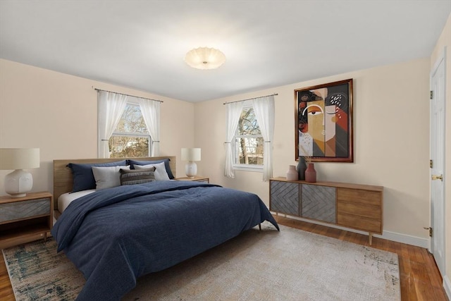 bedroom featuring multiple windows, wood finished floors, and baseboards