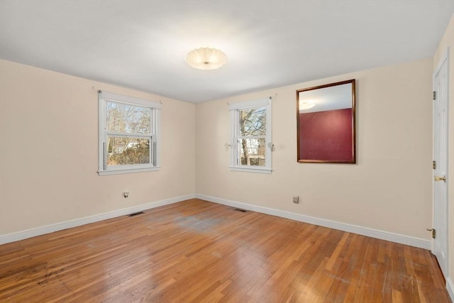 spare room featuring baseboards, visible vents, and light wood-type flooring