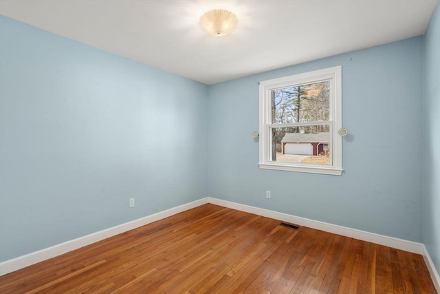 unfurnished room with baseboards and hardwood / wood-style flooring