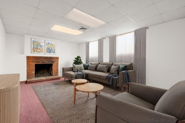 living room with visible vents, a paneled ceiling, a brick fireplace, and carpet flooring