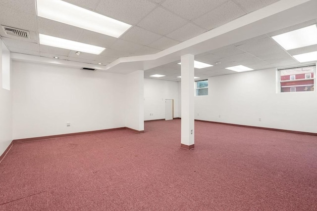 below grade area with carpet flooring, baseboards, visible vents, and a drop ceiling