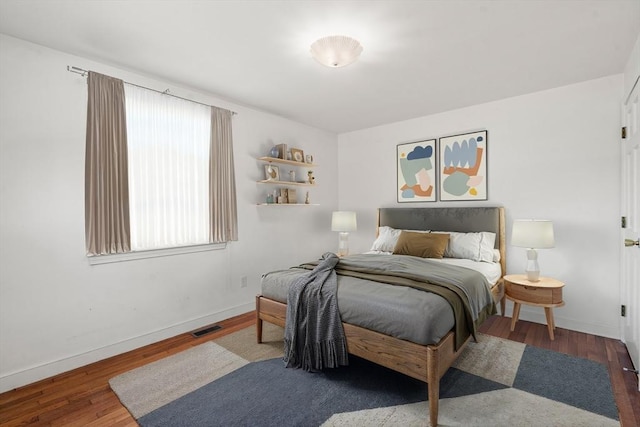 bedroom with visible vents, baseboards, and wood finished floors