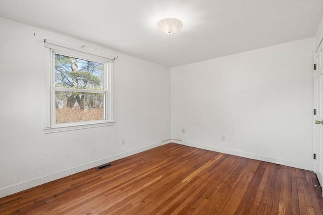 unfurnished room with hardwood / wood-style flooring, baseboards, and visible vents