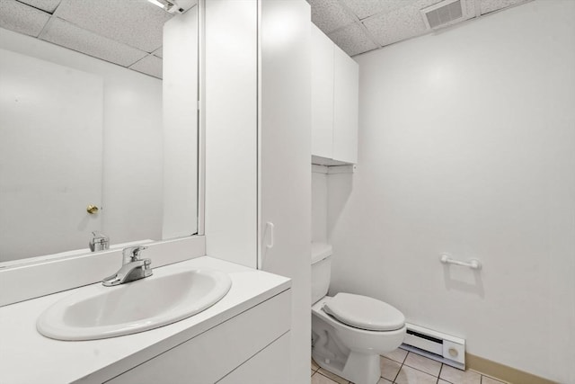 bathroom with toilet, baseboard heating, tile patterned floors, vanity, and a paneled ceiling