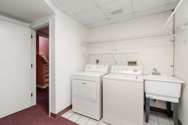 washroom with washing machine and clothes dryer, baseboards, light tile patterned floors, laundry area, and a sink