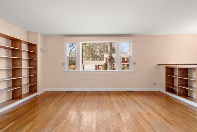 unfurnished room with visible vents, baseboards, and wood finished floors