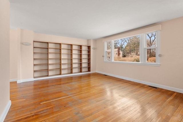 empty room featuring light wood-type flooring, baseboards, and visible vents