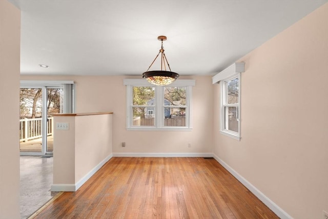 unfurnished dining area featuring baseboards and hardwood / wood-style floors