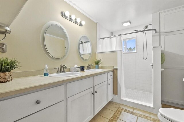 full bathroom with double vanity, a tile shower, and a sink