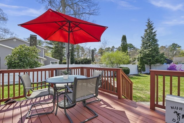 deck with a fenced backyard, outdoor dining space, and a lawn