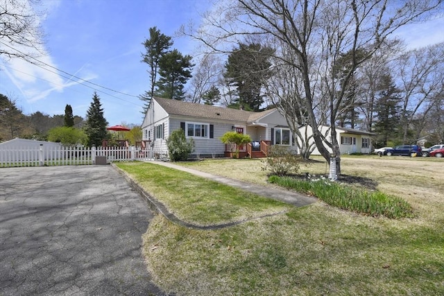 view of front of home with fence, driveway, and a front lawn