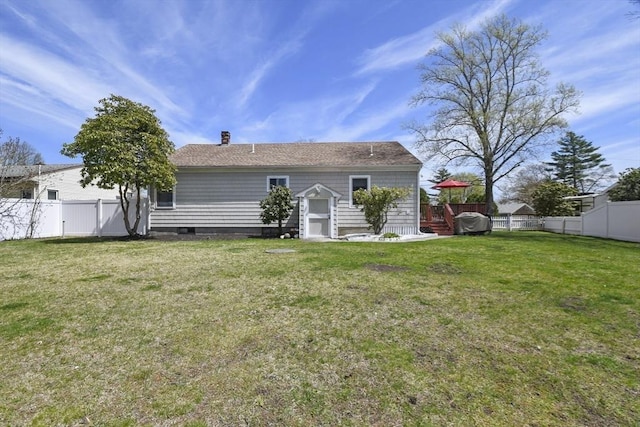 back of house with a fenced backyard, a chimney, and a yard