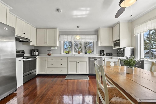 kitchen featuring crown molding, light countertops, under cabinet range hood, dark wood finished floors, and stainless steel appliances