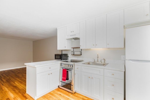 30 Danbury Dr Unit 8, Methuen, MA 01844 - kitchen with freestanding refrigerator, stainless steel range with electric stovetop, under cabinet range hood, white cabinetry, and light wood-type flooring