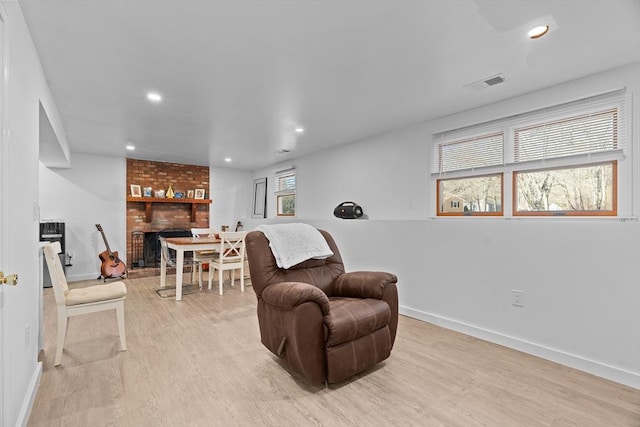 living area with light wood-type flooring, visible vents, recessed lighting, baseboards, and a brick fireplace