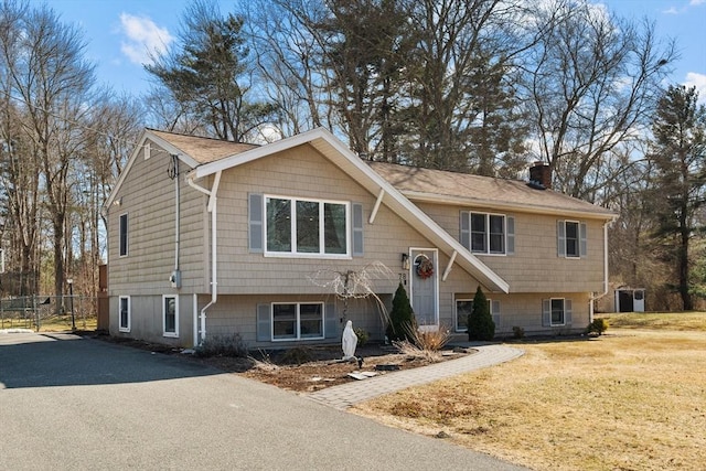 split foyer home with driveway, a front yard, and a chimney